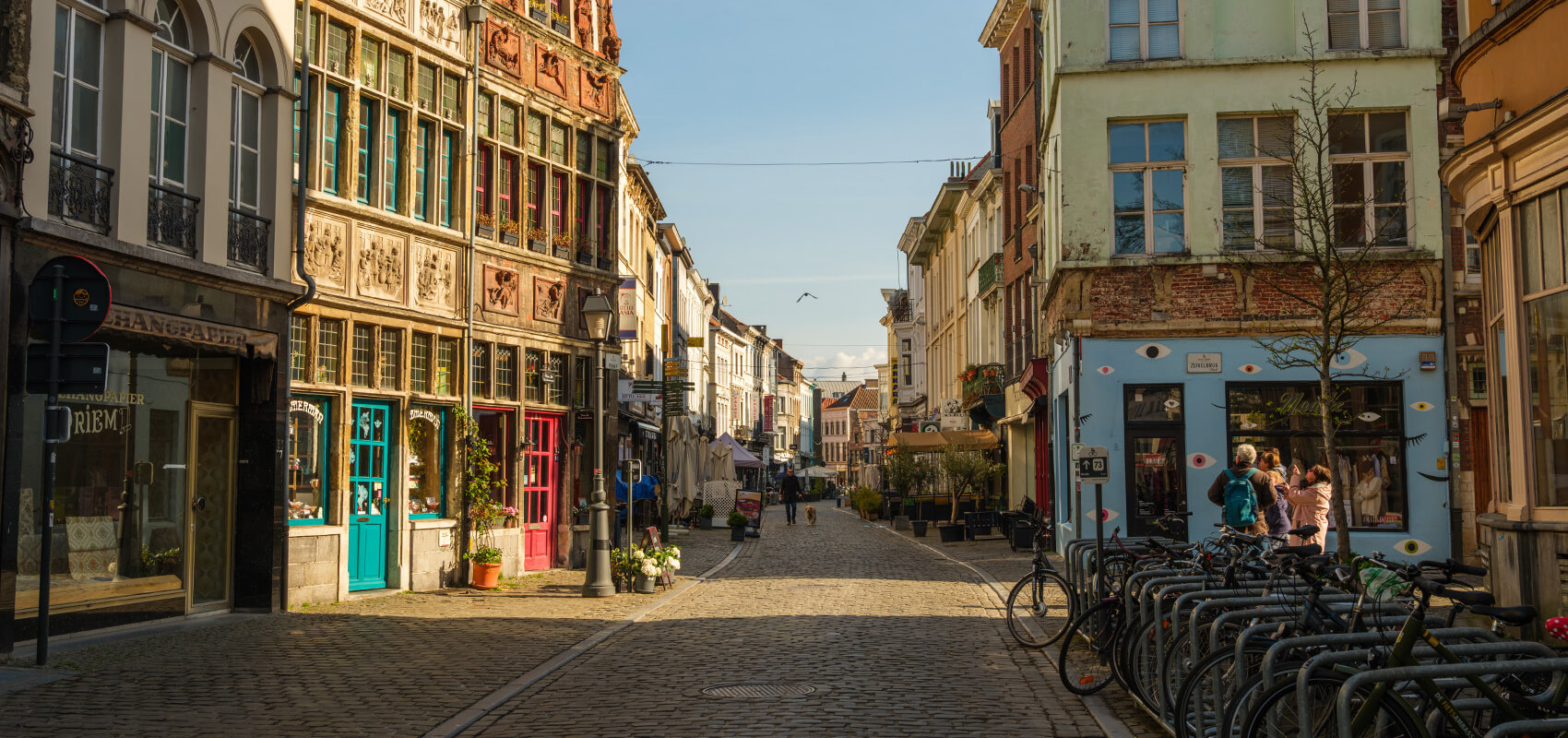 People walking along a charming cobblestone street in Ghent's historic centre